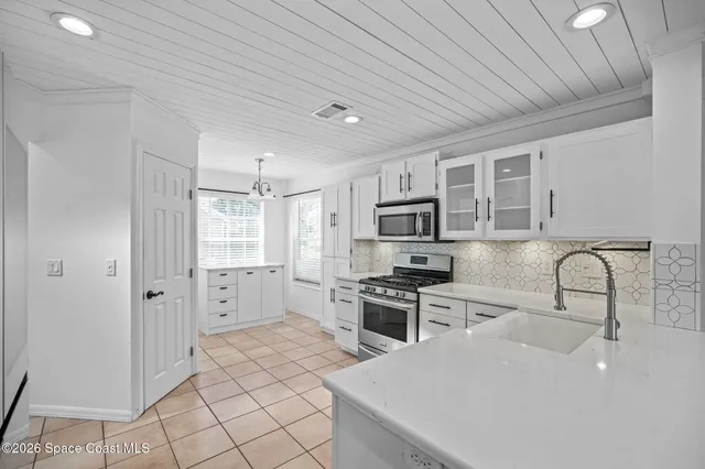 a kitchen with stainless steel appliances a stove a sink a refrigerator cabinets and a dining table