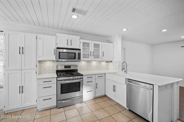 a kitchen with white cabinets and appliances