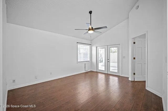 a view of an empty room with wooden floor and a window