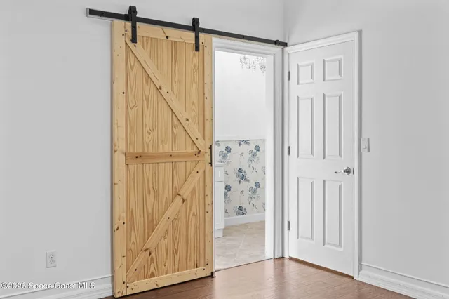 a room with a chandelier fan and wooden floor