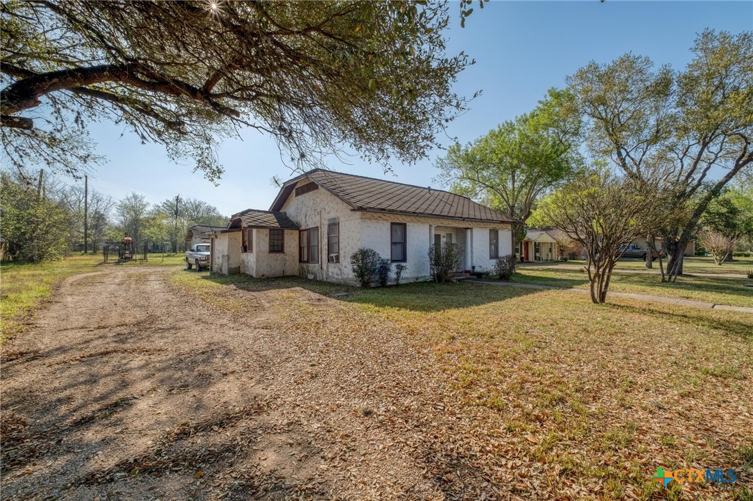 809 South Pecan Avenue Luling, TX 78648 - Photo 4 of 26 a front view of a house with a yard tree and wooden fence