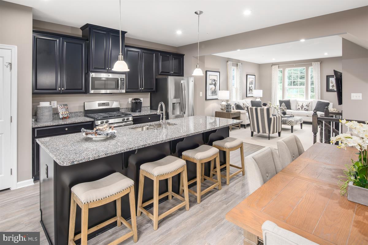 a large kitchen with a table chairs wooden cabinets and stainless steel appliances