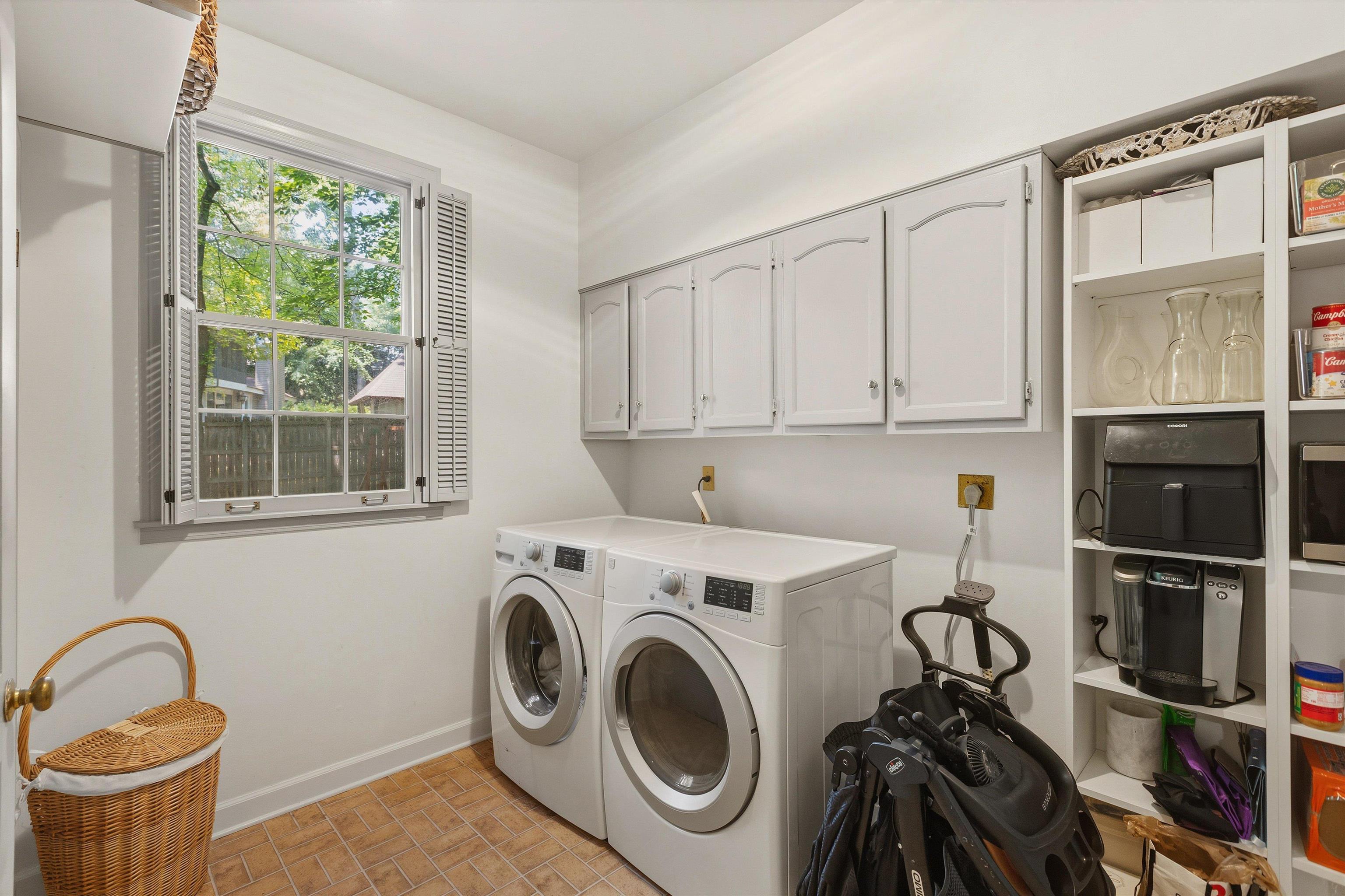 5828 Haymarket Road Memphis, TN 38120 - Photo 18 of 40 Dedicated laundry area featuring front-loading washer and dryer, upper cabinetry, open shelving, and a window with louvered shutters