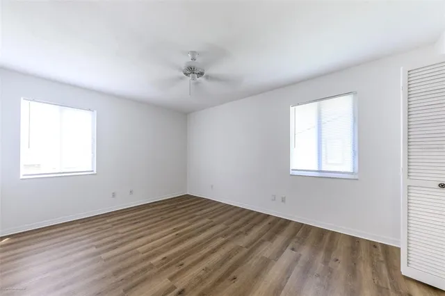 a view of empty room with wooden floor and fan