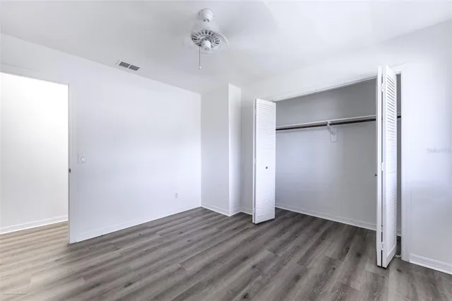 a view of an empty room with wooden floor and closet