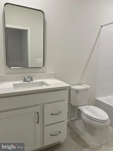 a bathroom with a granite countertop toilet sink and mirror