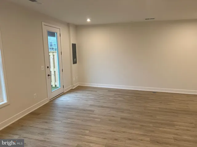 a view of an empty room with wooden floor and entrance