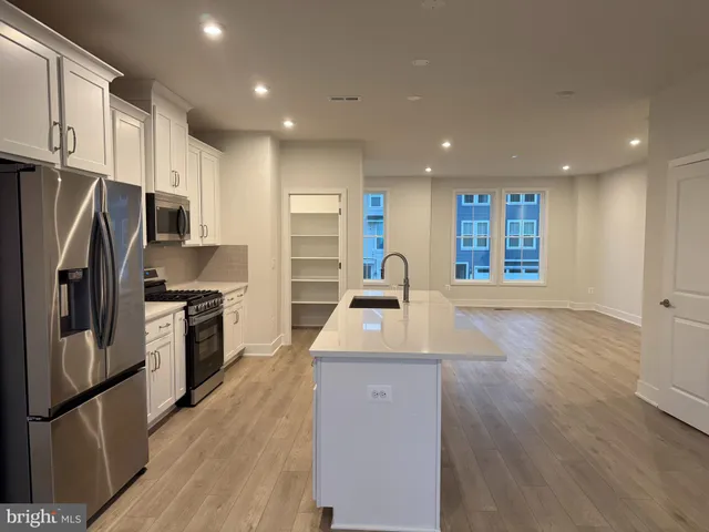 a kitchen with stainless steel appliances granite countertop a refrigerator a sink a stove a microwave oven and a refrigerator with wooden floor