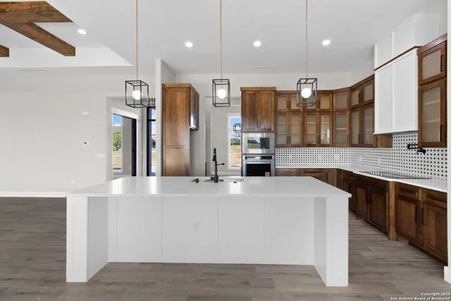 a large kitchen with stainless steel appliances a large counter top a stove and a sink