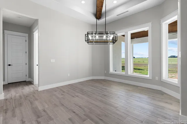 a view of an empty room with wooden floor fridge and a window