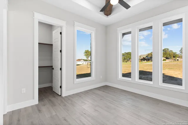 a view of an empty room with a window and wooden floor