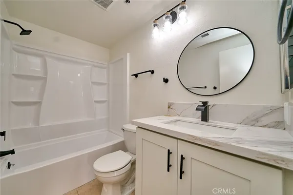 a bathroom with a granite countertop toilet a sink and a mirror