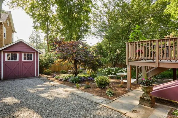 a view of a house with a small yard plants and large tree