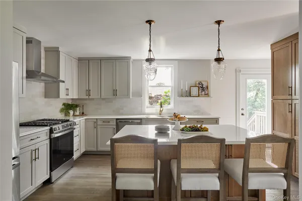 a kitchen with stainless steel appliances granite countertop a stove a sink dishwasher a refrigerator with a dining table and chairs