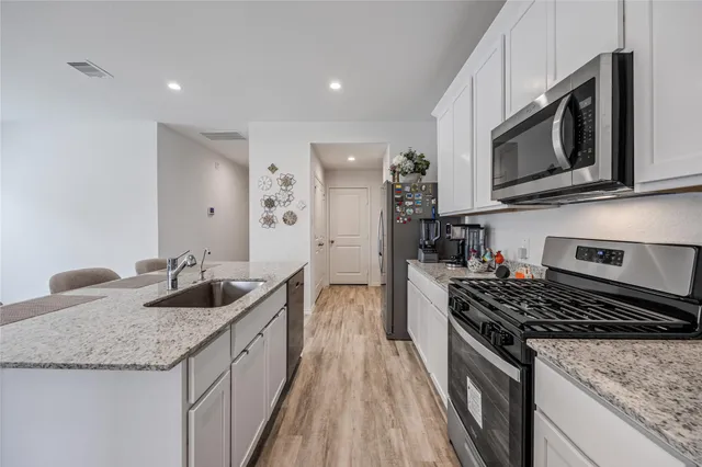 a kitchen with granite countertop stainless steel appliances a stove sink and microwave