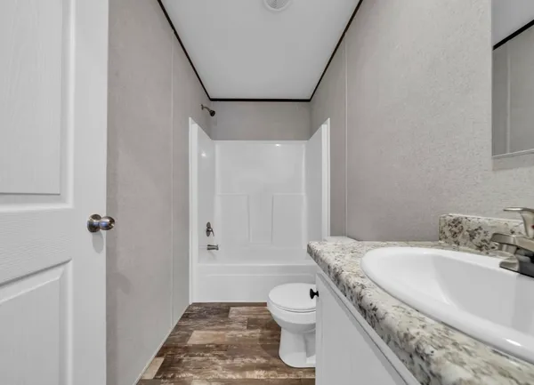 a bathroom with a granite countertop sink a toilet and shower