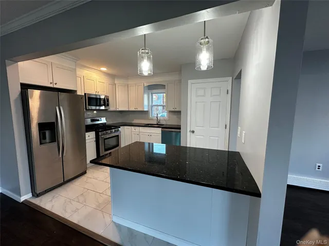 a large kitchen with a stove a sink dishwasher a refrigerator and a stove top oven with wooden floor