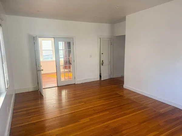 a view of an empty room with wooden floor and a window