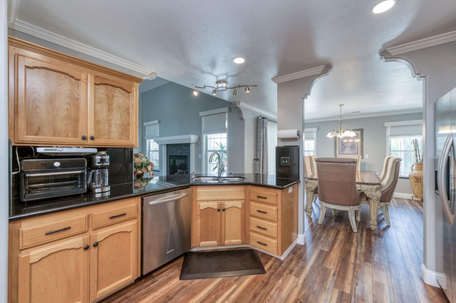 25106 Ave 18 Madera, CA 93638 - Photo 11 of 66 a kitchen with stainless steel appliances granite countertop a stove top oven a sink dishwasher a dining table and chairs with wooden floor