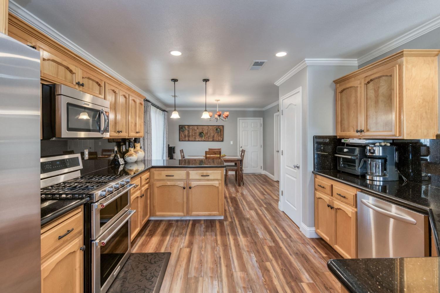 25106 Ave 18 Madera, CA 93638 - Photo 9 of 66 a kitchen with stainless steel appliances a stove top oven a sink a refrigerator white cabinets and wooden floor