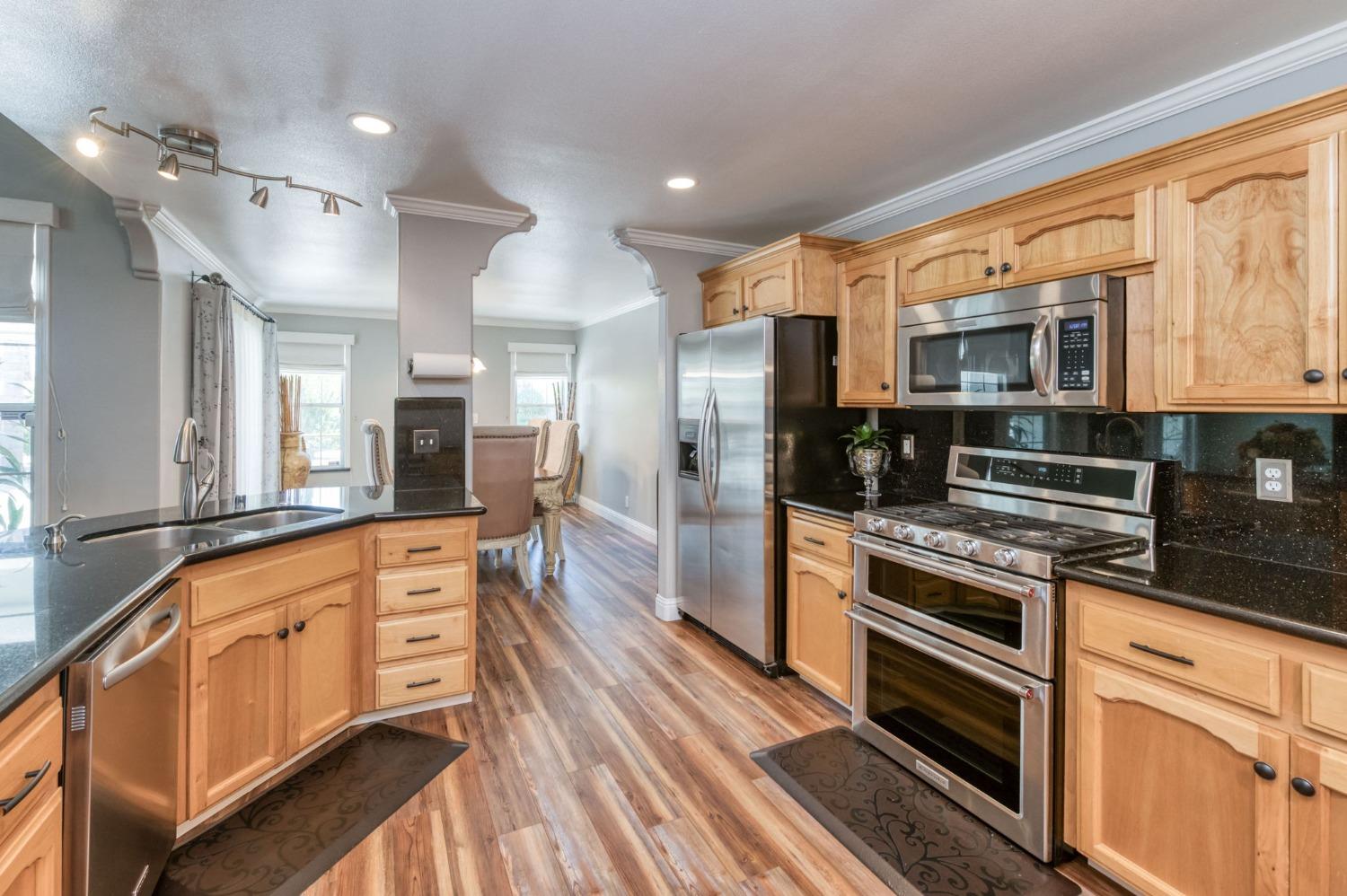25106 Ave 18 Madera, CA 93638 - Photo 10 of 66 a kitchen with stainless steel appliances a stove top oven a sink dishwasher a refrigerator and white cabinets with wooden floor