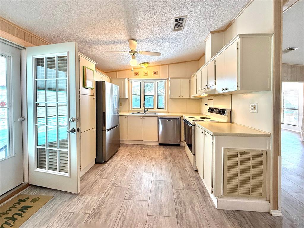 108 North St George Circle Apollo Beach, FL 33572 - Photo 7 of 34 a kitchen with stainless steel appliances granite countertop a refrigerator a sink dishwasher a stove and a dining table with wooden floor