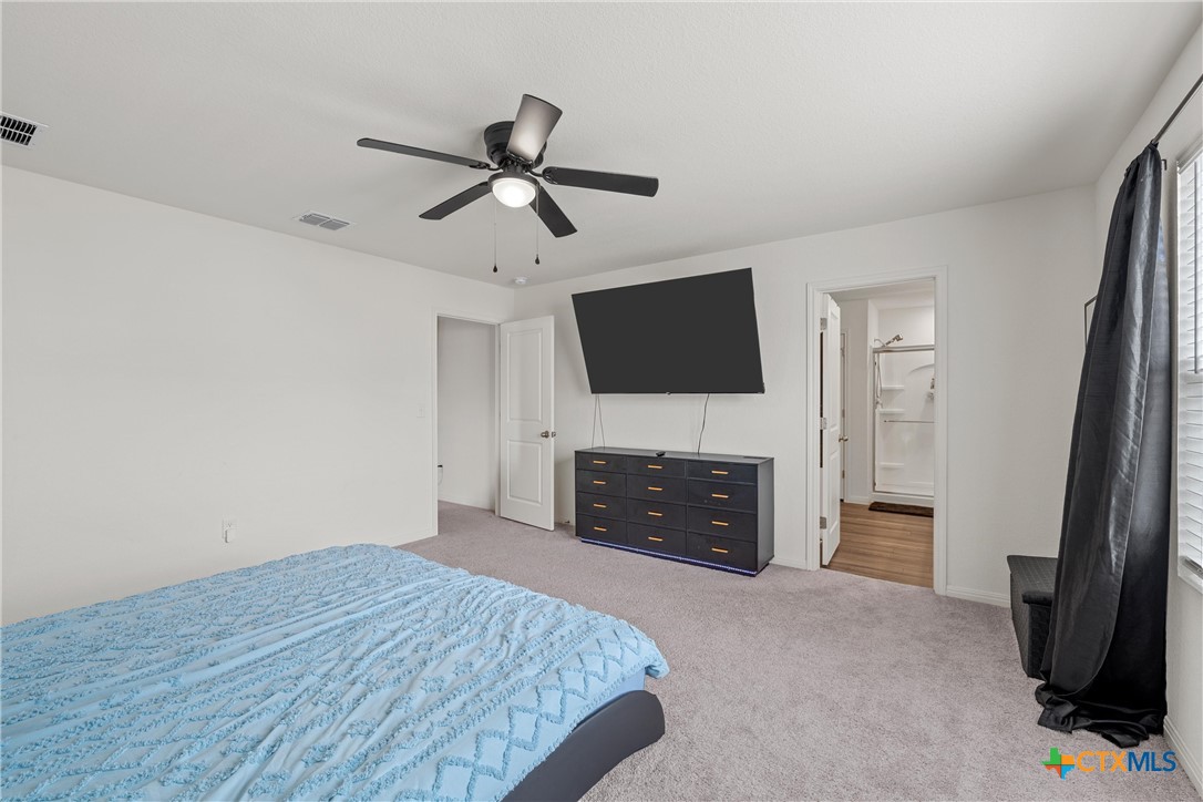 121 Sudden Impact Drive Jarrell, TX 76537 - Photo 14 of 38 a spacious bedroom with a bed and a flat screen tv