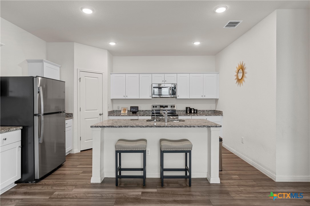 121 Sudden Impact Drive Jarrell, TX 76537 - Photo 9 of 38 a kitchen with stainless steel appliances granite countertop a white cabinets and wooden floor