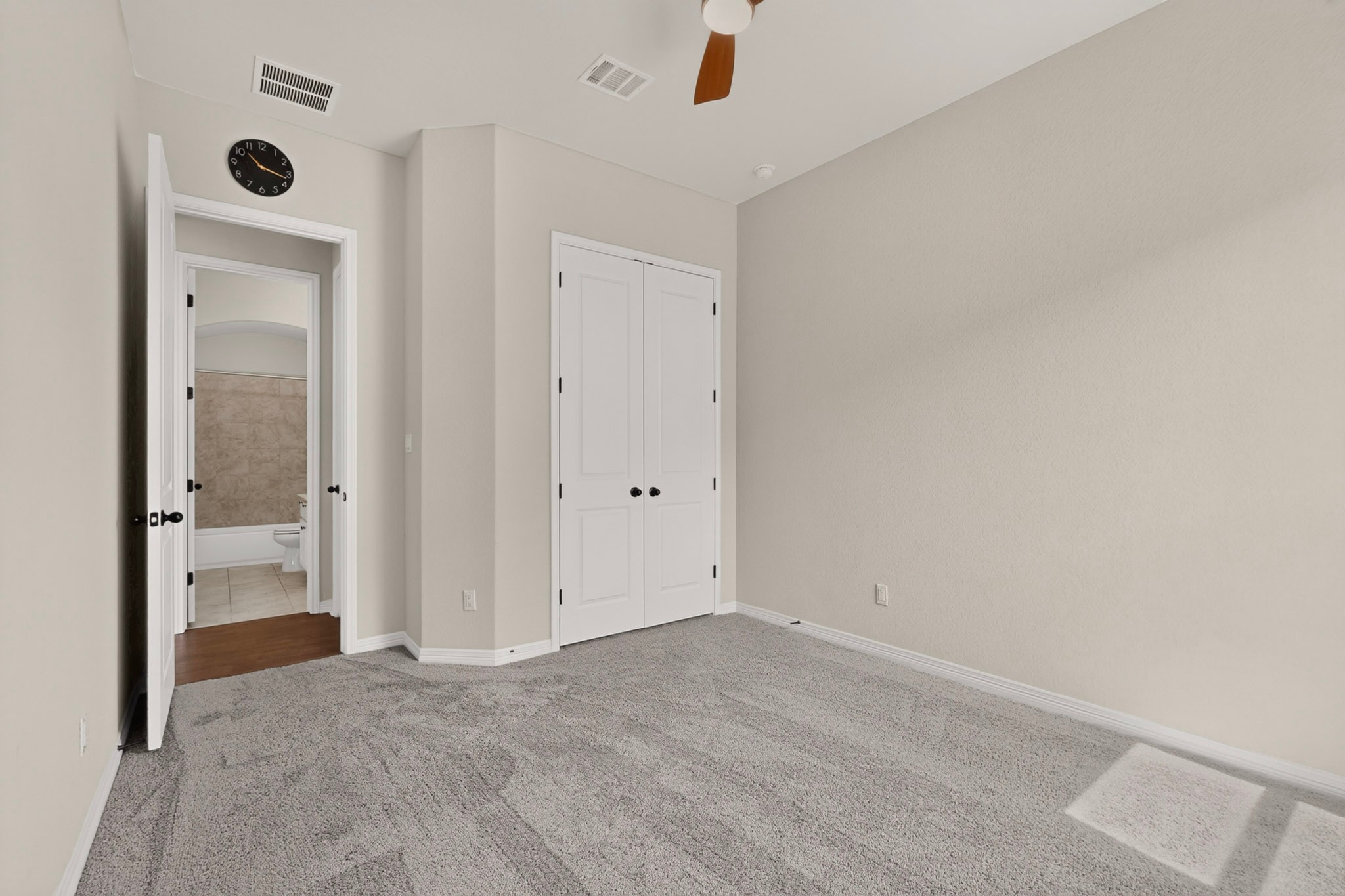 2433 La Mirada Street Leander, TX 78641 - Photo 15 of 25 A restful chamber offers soft gray carpet and a convenient closet, with a private bathroom accessible through an open doorway.