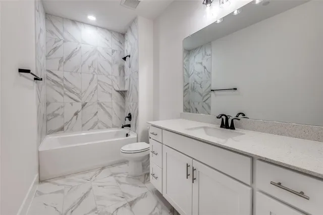 a bathroom with a granite countertop sink a toilet and bathtub