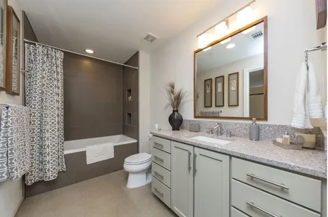 a bathroom with a granite countertop sink a toilet a mirror and shower