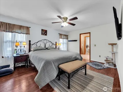 a bedroom with a bed a dresser and wooden floor