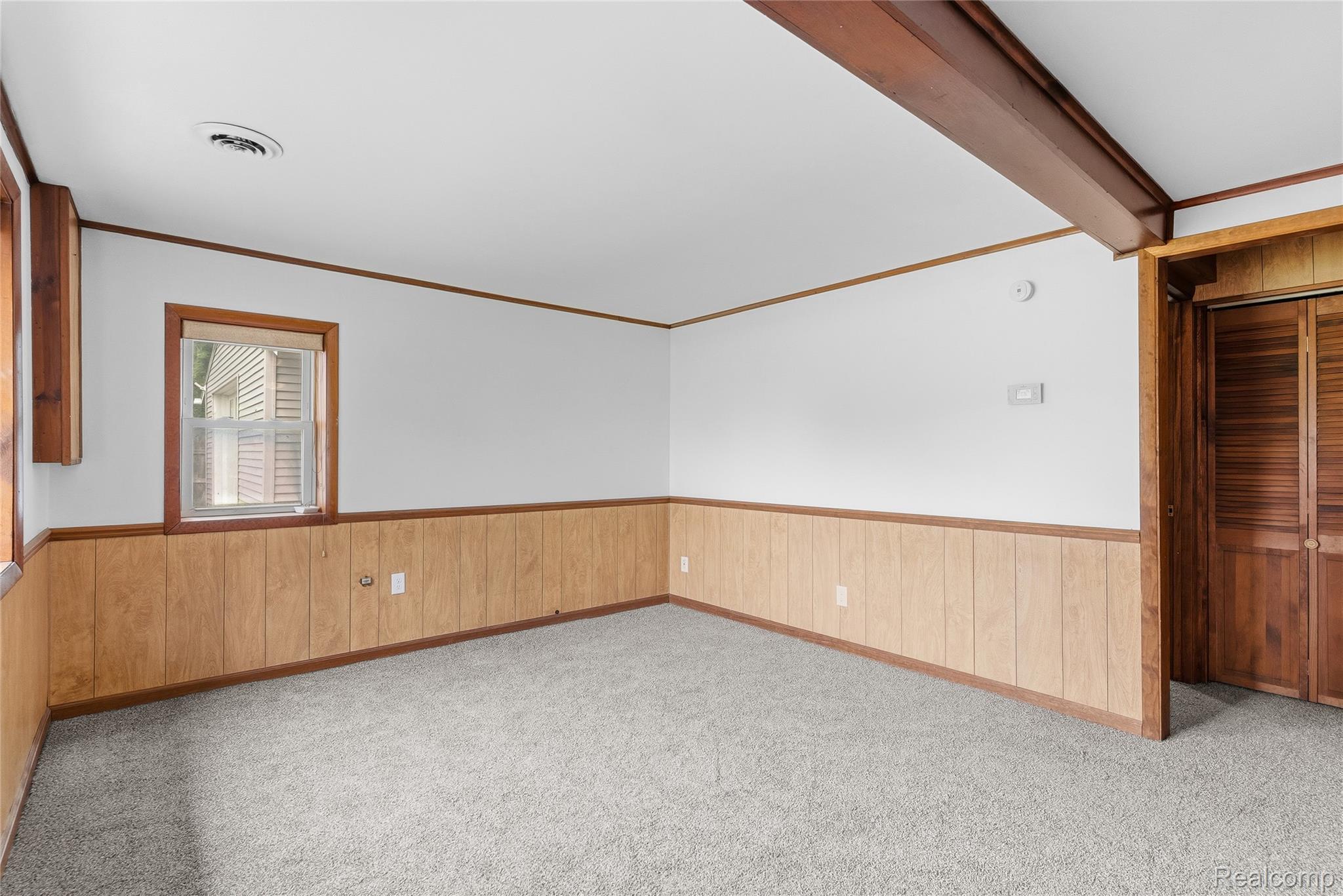 1843 Curtis Road Birch Run, MI 48415 - Photo 11 of 25 Carpeted room featuring wood paneling, white walls, and exposed wood beam