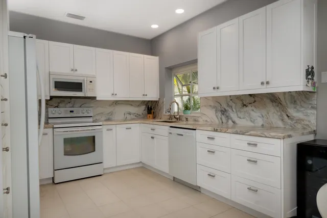 a kitchen with granite countertop white cabinets and white appliances