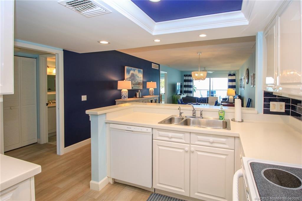 20 Northeast Plantation Road, Unit 205 Jensen Beach, FL 34957 - Photo 15 of 30 a kitchen with kitchen island a sink and a stove with wooden floor