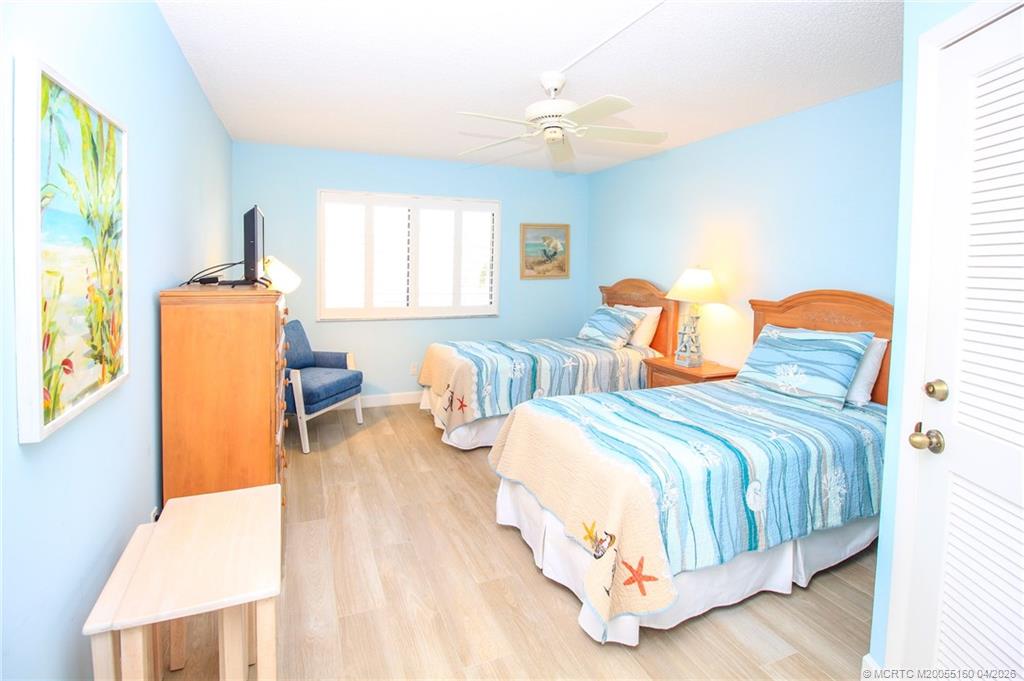 20 Northeast Plantation Road, Unit 205 Jensen Beach, FL 34957 - Photo 21 of 30 a bedroom with two beds and a chandelier