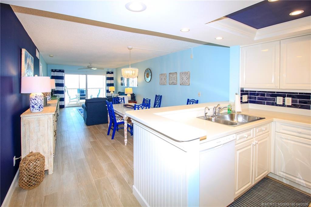 20 Northeast Plantation Road, Unit 205 Jensen Beach, FL 34957 - Photo 6 of 30 a kitchen that has a lot of cabinets a sink and a dining table with chairs