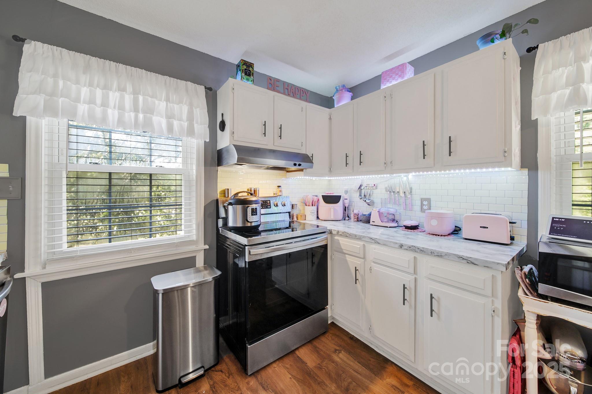 1517 University Drive Lancaster, SC 29720 - Photo 23 of 29 a kitchen with a stove a sink and white cabinets with wooden floor