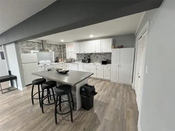 a kitchen with refrigerator and wooden floor