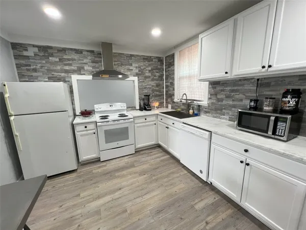 a white kitchen with a stove top oven and white cabinets