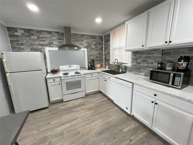 a white kitchen with a stove top oven and white cabinets