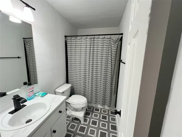 a bathroom with a sink a toilet and shower curtain
