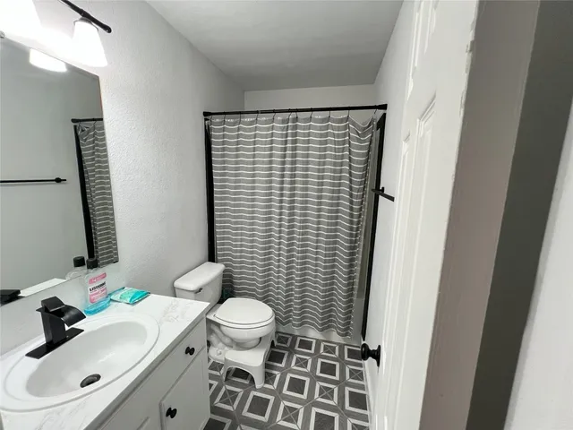 a bathroom with a sink a toilet and shower curtain
