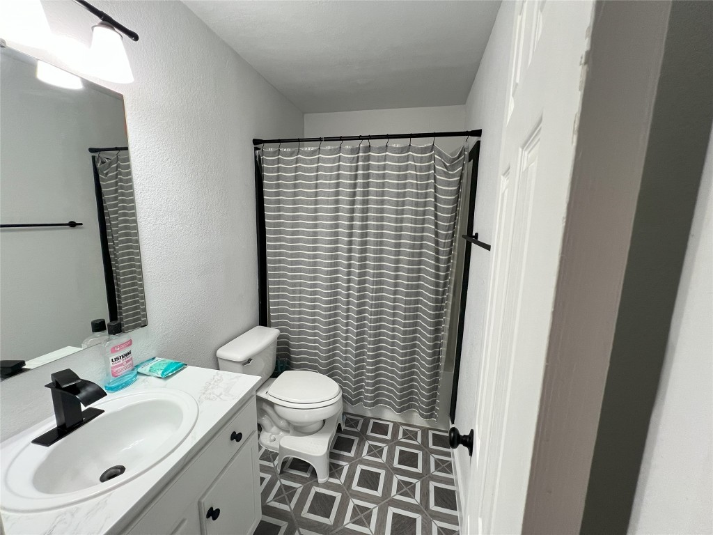 128 Skyview Terrace, Unit B Leander, TX 78641 - Photo 8 of 24 a bathroom with a sink a toilet and shower curtain