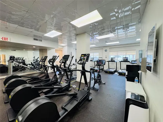 a gym room with lots of gym equipment and wooden floor