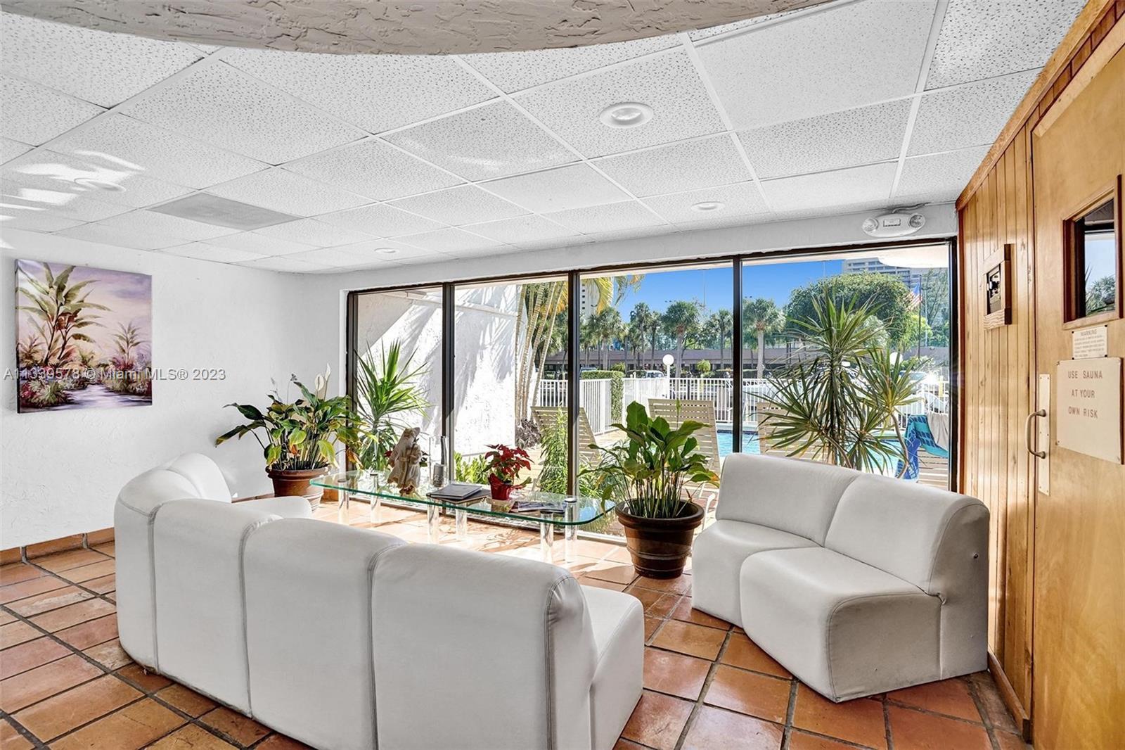 1650 Northeast 115th Street, Unit 102 Miami, FL 33181 - Photo 26 of 35 a living room with furniture potted plant floor to ceiling windows and plants
