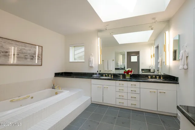 a bathroom with a sink a large mirror and a bathtub