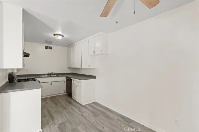 a kitchen with granite countertop a stove top oven a sink dishwasher and a refrigerator with wooden floor