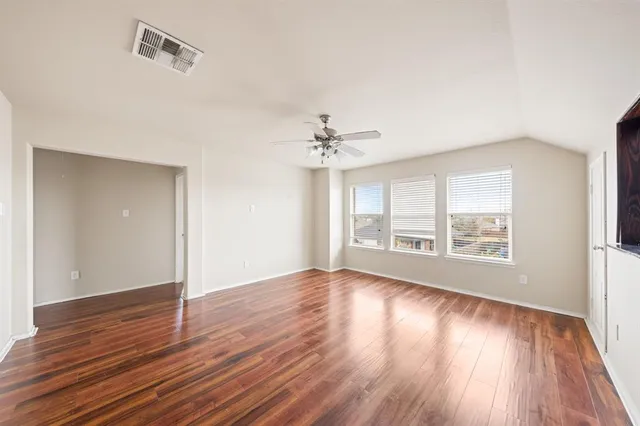 an empty room with wooden floor and windows