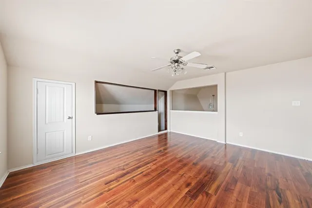 a view of an empty room with wooden floor and cabinet